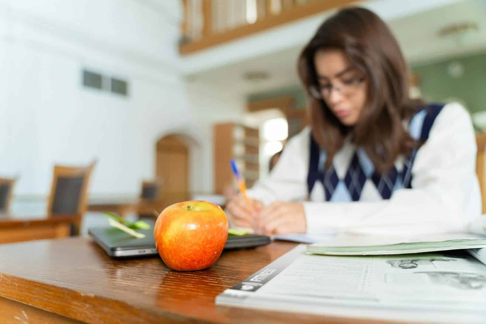 Student studying with notes and an apple on a desk, symbolizing education and focus.